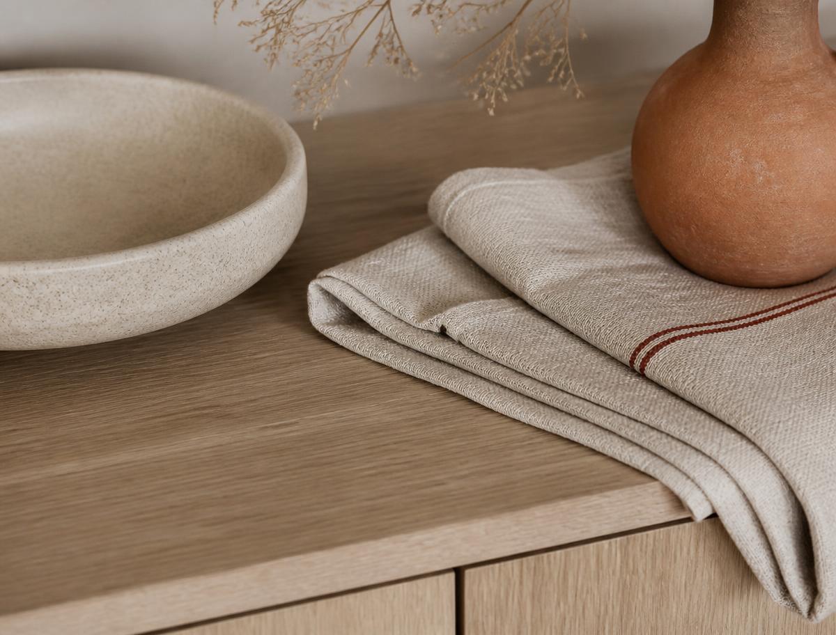 Detalj fra praksisen med lys eikeflate, brettet lintekstil og en keramikkskål